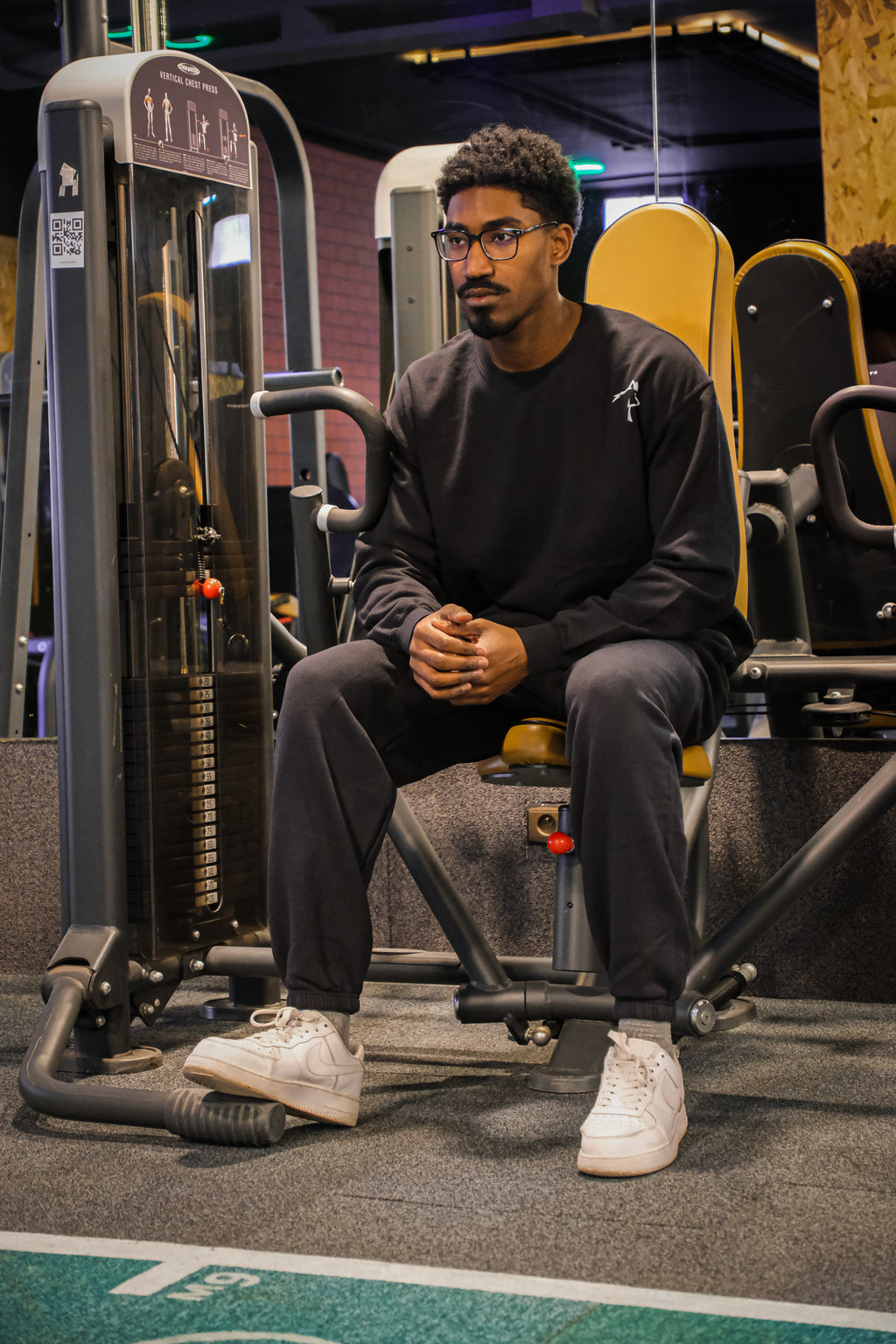 Man sitting on a piece of exercise equipment in a gym