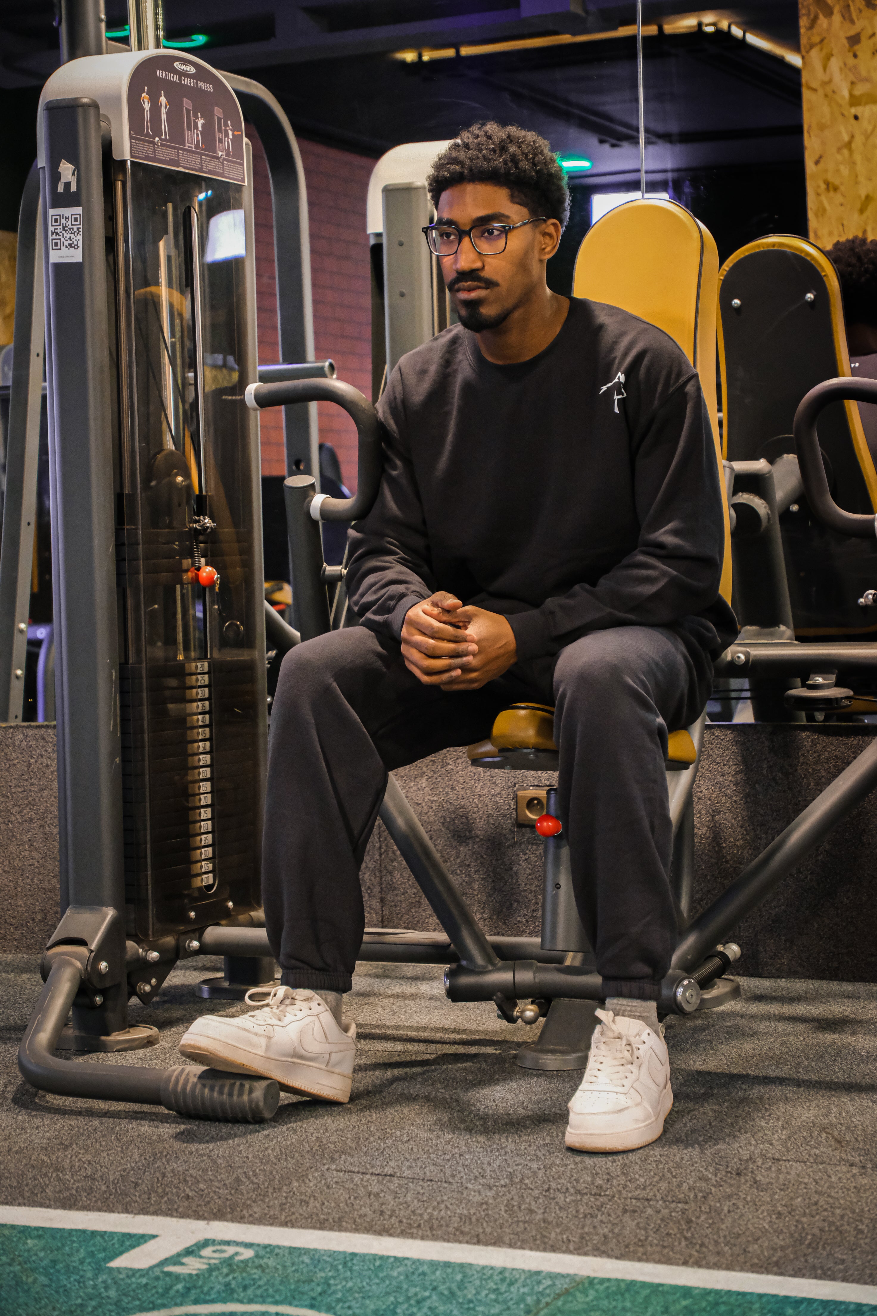 Man sitting on a piece of exercise equipment in a gym