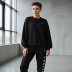 Person wearing a black sweatshirt and black pants with 'Gym Wear' text in a minimalistic room.